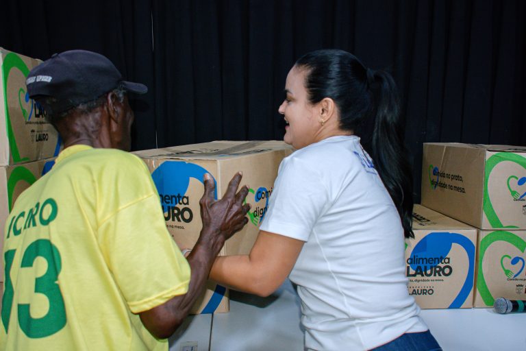 Prefeita Débora Regis entrega cesta básica do programa Alimenta Lauro para moradora no CRAS de Itinga; kit contém 31 itens essenciais.