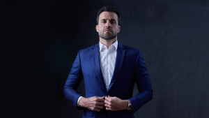 O influenciador Pablo Marçal, vestindo terno azul e com expressão séria, ajeita o paletó; imagem ilustra a notícia sobre as restrições judiciais impostas após o caso do laudo falso