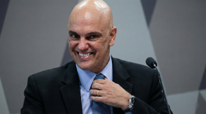 Ministro Alexandre de Moraes ajusta a gravata e sorri; imagem ilustra a decisão de quebra de sigilo de servidores suspeitos de vazar dados do STF