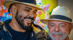 O ator Paulo Vieira e o presidente Lula sorrindo lado a lado usando chapéus; imagem ilustra a relação de amizade e o convite pessoal para o desfile.