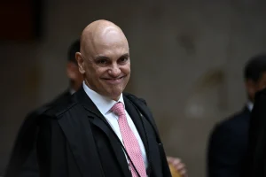 Ministro Alexandre de Moraes em close, sorrindo de forma sutil; a imagem ilustra a notícia sobre a troca estratégica de seu celular antes do vazamento de conversas com Daniel Vorcaro.