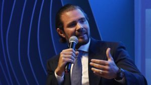 O empresário Daniel Vorcaro, dono do Banco Master, gesticula enquanto fala ao microfone em um evento; a imagem ilustra o pedido de sua defesa para barrar gravações no parlatório da prisão.