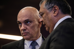 O ministro Alexandre de Moraes à esquerda e o ministro Flávio Dino à direita conversando de perfil no plenário do STF; imagem ilustra a matéria sobre a cobrança contra supersalários no Judiciário em 2026.