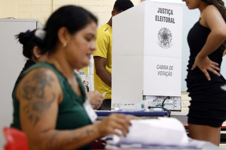 Eleitores em fila para votar em urna eletrônica